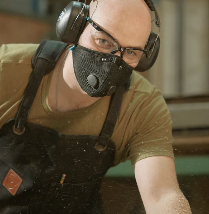 Person wearing an RZ M2 Mask and ear protection in a workshop setting
