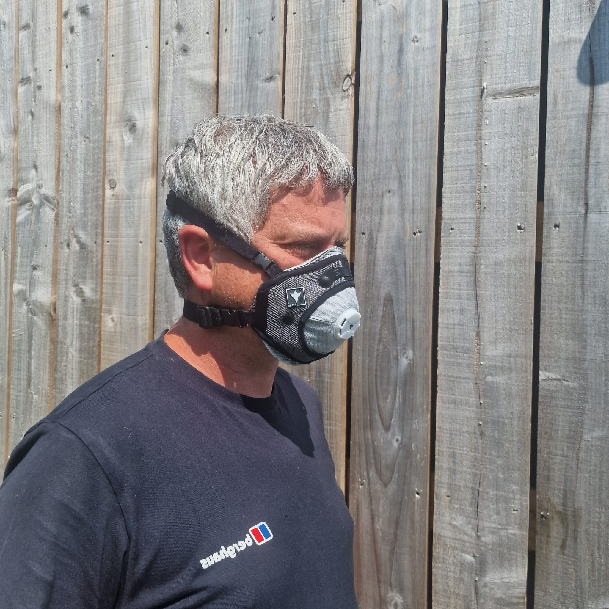 Man wearing a RZ Pro FFP3 mask against a wooden fence