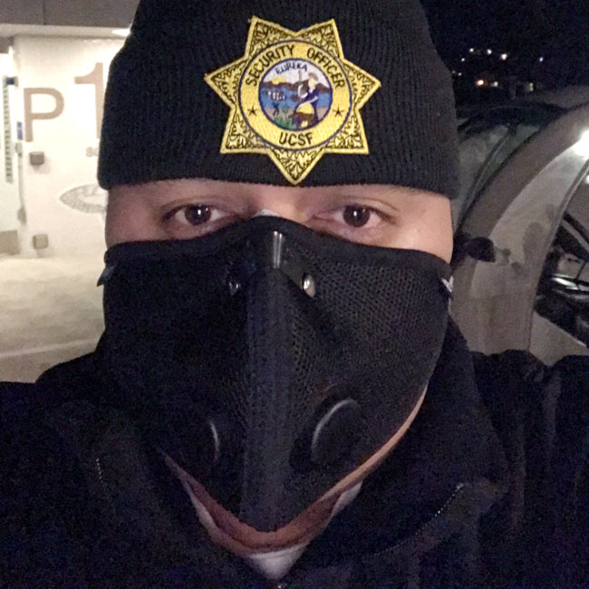 Security officer wearing an rz mask m2 black mask to protect against particulates while on the job at a correctional facility.