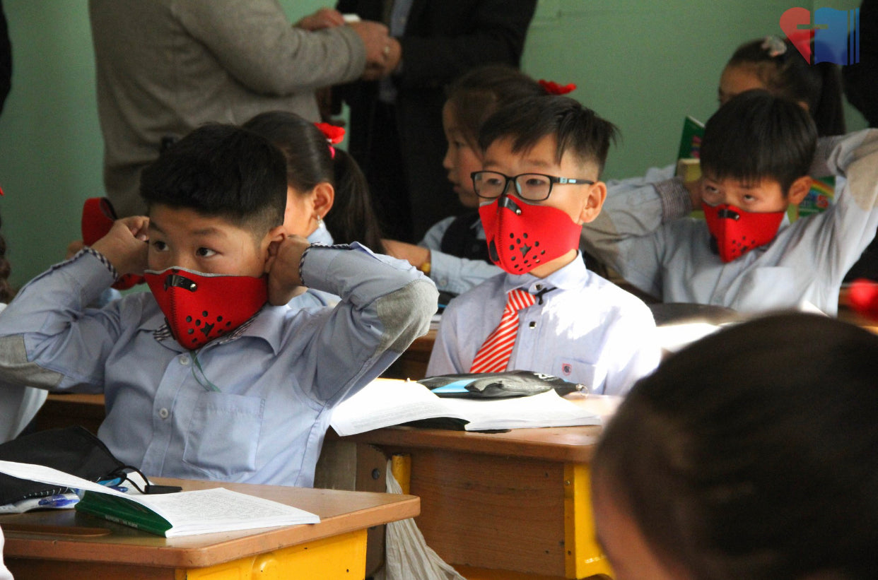 Image of three mongolian boys wearing rz mask m1 red masks in a classroom to protect against pollution in their city.