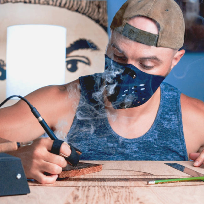 man wearing rz mask m1 neoprene mask while doing a woodburning project