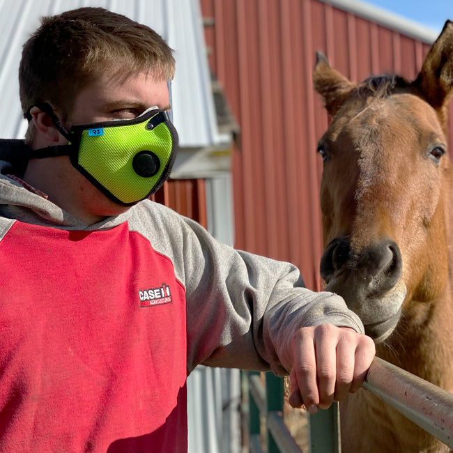 farmer wearing an rz mask m2.5 safety yellow while standing next to a happy horse.