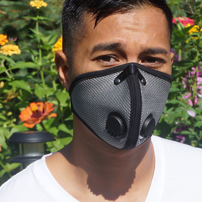 a man wearing an m2 titanium rz mask while standing in a garden to protect from pollen and other allergens
