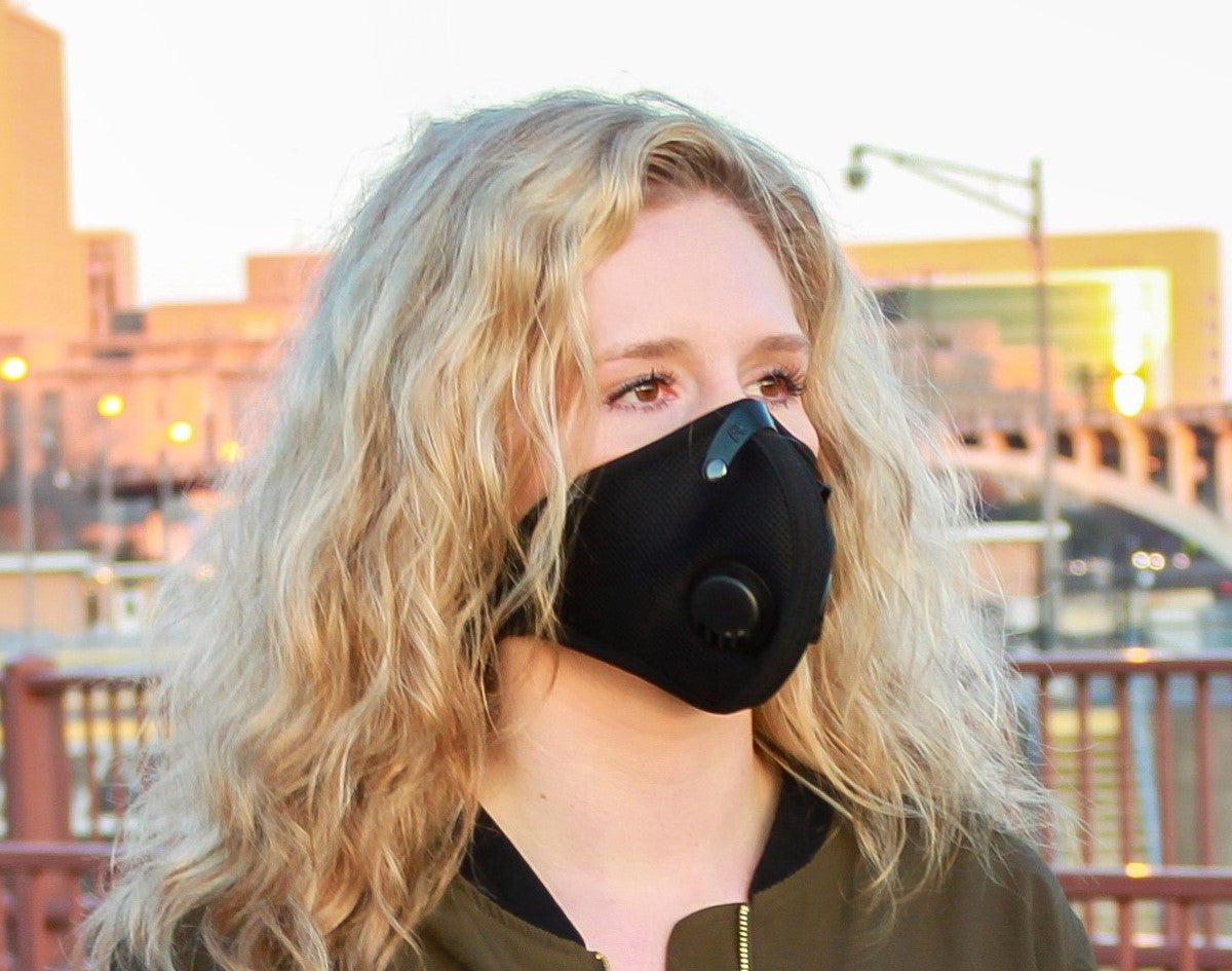 woman wearing rz mask m2 black on a bridge in a polluted city