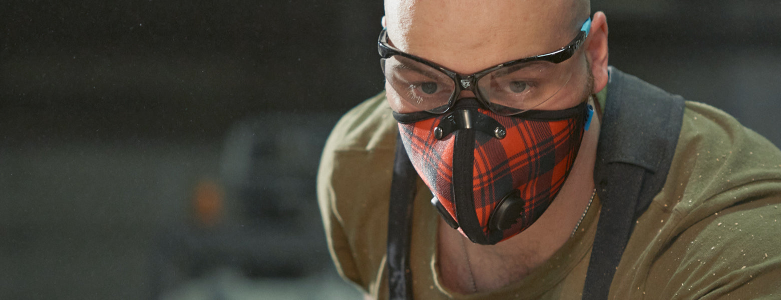 man wearing rz mask m2n red plaid mask while in a woodworking shop