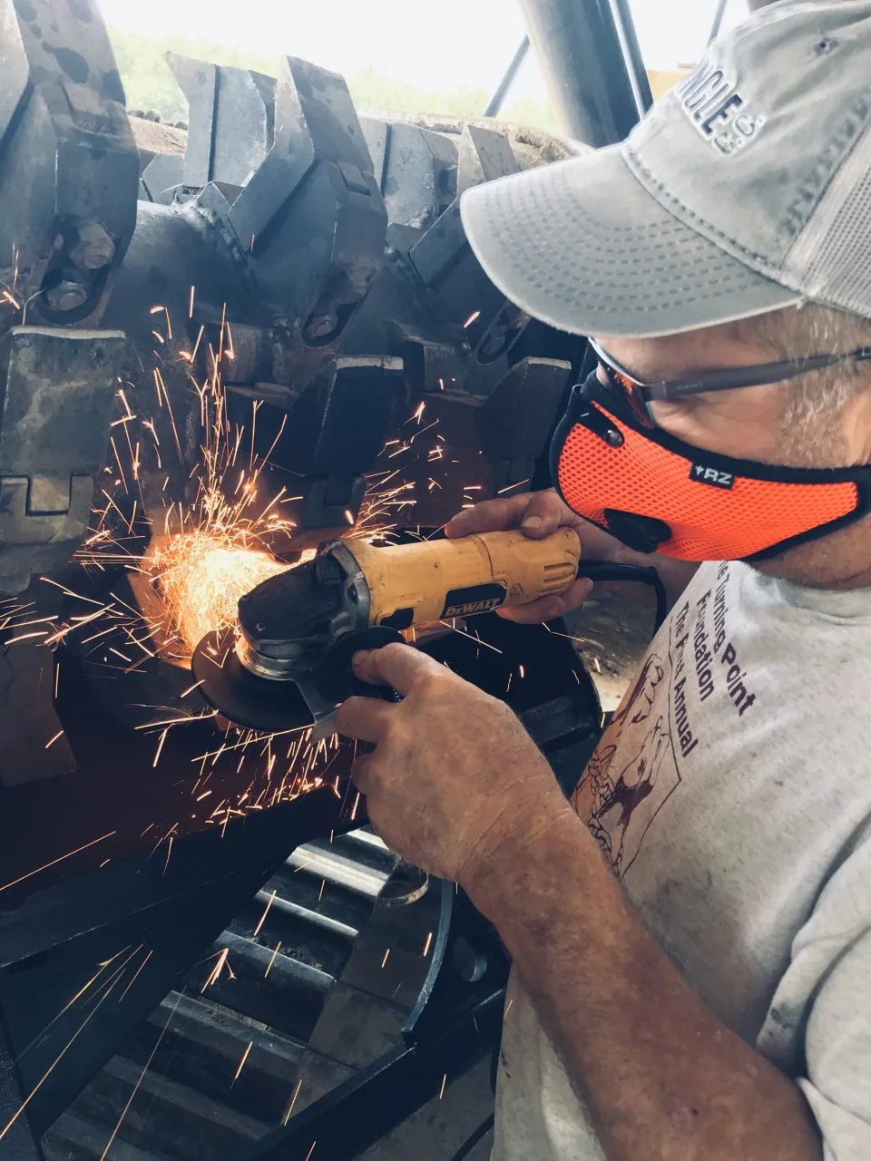 Worker wearing an orange RZ mask while grinding a metal component