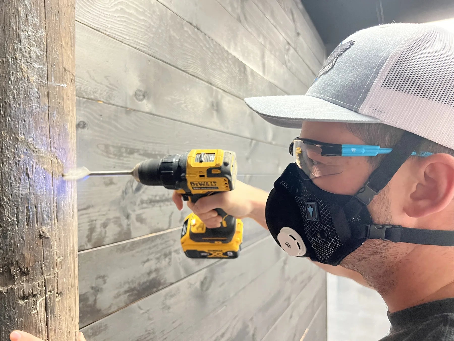 A worker wearing an RZ mask while using a drill